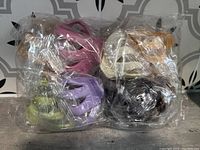 Photo of the eight individually wrapped hair clamps in assorted colors inside clear plastic packaging.