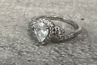 Close-up front view of the 925 silver ring showing pear-shaped center stone and accent stones around and on the band.