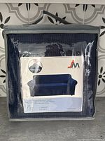 Packaged navy blue stretch chair cover with product image and description showing usage on a sofa/chair.