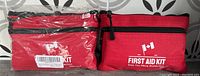 Two red compact first aid kit pouches with black zippers and Canadian flag logo on the front, one sealed in plastic, one unpackaged