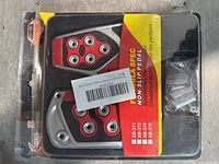 Photo of non-slip pedal covers in packaging showing red and black pedal pads with silver studs and included screws.