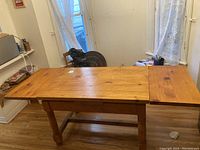 Table shown with one leaf extended, showcasing the construction and style of the legs and tabletop extension.