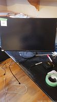 Full front view of the ASUS monitor showing screen and base stand on black desk.