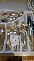Tray of forks, knives, and spoons with detailed decorative handles showing the variety of pieces included in the set.