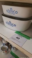 Two stacked rectangular Corningware casserole dishes with lids, featuring Blue Cornflower pattern on the side.