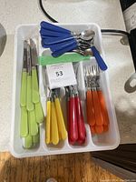 Photo of a white cutlery organizer tray containing knives, teaspoons, and forks with colorful plastic handles.