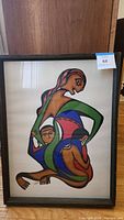 Full front view of framed print showing abstract mother and child composition in wood frame with lot tag attached