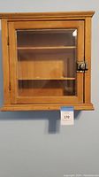 Front view of the wooden display case showing glass door and metal latch.