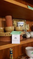 Wooden seder plate with Hebrew text, four wooden bowls, kosher salt box and two ceramic birds on wooden shelf