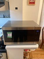 Front view of LG microwave with closed door showing digital display and control panel.