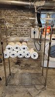 Front view of metal wire shelving unit with several rolls of paper towels on two shelves.