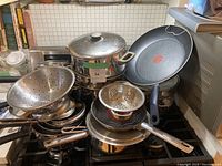 Side view of whole lot showing various pots, strainers, and a frying pan with a heat indicator.