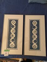 Two framed serigraph prints laid flat on blue surface