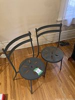 Two solid metal outdoor chairs seen from above and front showing curved backrests and circular seats with cutouts