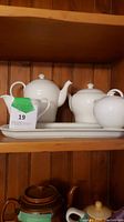 Teapot, sugar bowl, creamer and tray displayed on shelf