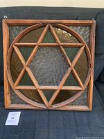 Full view of stained glass panel with wooden frame, Star of David design, approx. 20x20 inches.