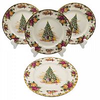 Four Royal Albert Christmas Magic Old Country Roses tea plates shown on stands, front view displaying Christmas tree center and floral border.