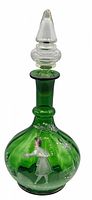 Full view of the green glass decanter with hand-painted Mary Gregory style white enamel decoration and clear glass stopper with gold paint.