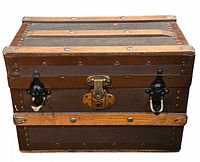 Front view of antique miniature trunk showing lock and clasps on textured brown surface with wooden slats