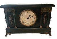 Front view of the black wooden Sessions mantle clock with gold decorative feet, ornamental designs, green faux marble panels, and columns. Clock face is cream-colored with black numbers and 'Sessions' logo.