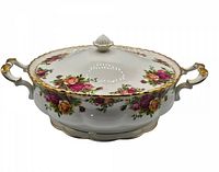 Front and side angle of the covered tureen showing floral pattern and gold trimmed handles and lid.