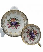 Paragon wide mouth tea cup and saucer set shown with fruit and floral pattern and gold decorative trim, both items displayed on a white stand.