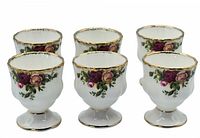 Set of six Royal Albert Old Country Roses egg cups arranged in two rows showing front rose pattern and gold rims.