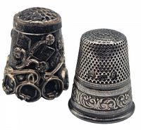 Photo of two vintage sterling silver thimbles side by side showing detailed patterns and markings.