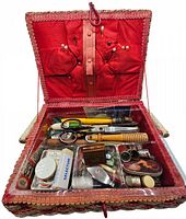 Top view of sewing box opened showing pins, scissors, rotary cutter, wooden handled tools and several small sewing accessories in compartments