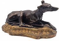 Side profile of reclining greyhound on ornate base
