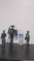 Three figurines including two cast iron geishas and one brass terra cotta statue next to a water bottle for scale.
