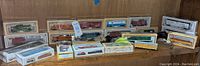 Full view of collection showing various boxed Bachmann and Life-Like model train cars arranged on wooden shelving, including freight cars, cabooses, and accessories.