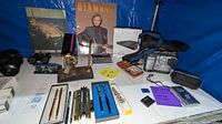 Wide view of lot showing Sony camcorder, pens, books, binoculars, and accessories