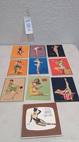 Lot of 10 vintage pinup girl cards arranged in two rows on a white surface.