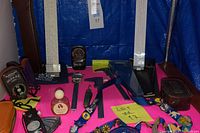 Overview of lot with exposure meter in pouch, calipers, rulers, metal slide rule, razor, and other items arranged on pink cloth.