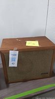 Single vintage Realistic Solo-1 wooden speaker showing front fabric grille and top wood surface with wear and tape marks.
