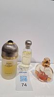 Three used perfume bottles next to MaxSold lot card 74