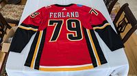 Back view of the red Calgary Flames hockey jersey with the name Ferland and number 79, showing Adidas logo, Canadian flag patch, and sleeve striping details.
