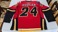 Full back view of the Calgary Flames Hudler jersey showing the name Hudler and number 24 in detail on a red background with black sleeves.