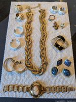 Full view of group jewelry collection on white fabric showing necklace, earrings, rings, brooch, and bracelet