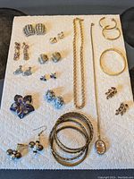 Full collection of vintage and costume jewelry laid out on a towel, showing various earrings, bracelets, and necklaces.