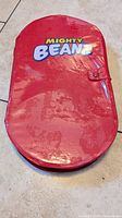 Closed red Mighty Beanz storage case with logo and snap clasp, showing surface wear and scratches.