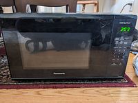 Front view of Panasonic NNSG626B microwave oven on a carpet, shows the door and appliance body.