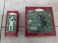 Photo showing the original boxes for both Star Wars Hallmark Keepsake Ornaments, Darth Maul and Imperial Stormtrooper, positioned side by side on a tiled surface.