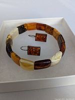 Set showing bracelet and pair of amber rectangular earrings in sterling silver on white display box.