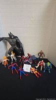 Wide angle of entire lot showing 11 action figures including Batman, Spider-Man, Dragon Ball character, Superman and others