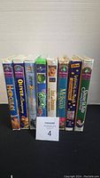 Side view of 8 Disney DVD cases standing upright showing titles: Hercules, Oliver & Company, The Grinch, 101 Dalmatians II, The Little Mermaid, Winnie the Pooh, Snow White.