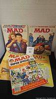 Lot of 4 visible Mad magazines arranged overlapping showing variety of covers including Top Gun parody and other special issues.