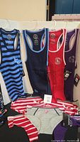 Four Ottawa Senators sleeveless shirts hanging on hangers, showing variety of colors and logos.