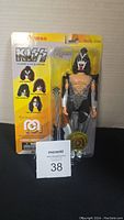 Photo showing Mego KISS The Demon figure in original packaging with yellow backing card and accessory mace, front view.